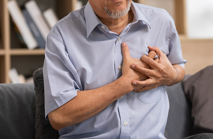 A close-up of an elderly man clutching his chest in pain, indicating potential heart disease.